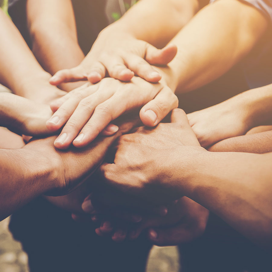 A Small Group of People in a Community with Their Hands in a Circle