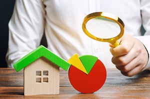 man holding a magnifying glass with wooden house model and pie chart | list of association management companies