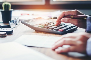 hands with calculator, analyzing counting on wood desk | hoa property management companies