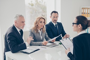 a group of people discussing while holding documents | hoa management companies