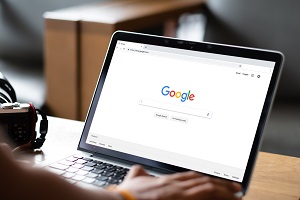 man is typing on Google search engine from a laptop | affordable property management companies in Charlotte, NC