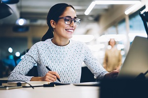 woman in glasses working on desk while smiling | role of an HOA secretary