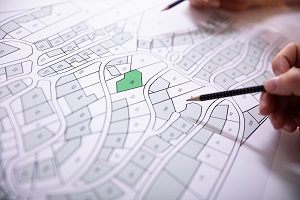 Hand Holding Pencil Over Cadastre Map | hoa event planning