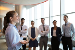 female leader with open hands gesture standing in front of her team in office hall | what is hoa management