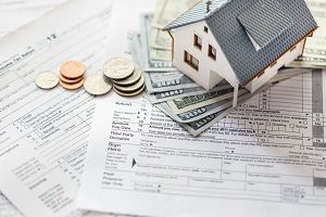 Miniature house with money on tax papers | homeowners association assessment