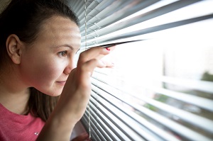woman watching out from the window | homeowners association neighborhood watch