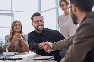 smiling man handshaking with another man with two women in the background | why hire an hoa management company