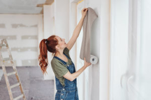 woman trying out new wallpaper at home | home ownership tax benefits