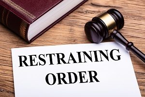 restraining order written on paper with gavel and law book background | hoa harassment law