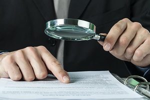 man looking at a document with magnifying glasses | hoa taxes