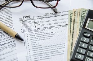 Form 1120 Tax Return with pen, glasses, calculator and money | hoa tax filing