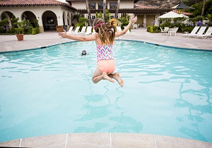 Child jumping into a big swimming pool | summer construction projects in the HOA
