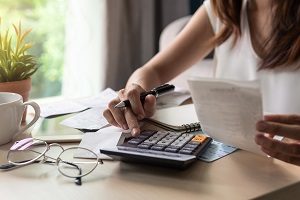 woman pressing calculator while holding a paper and pen | hoa financial mistakes