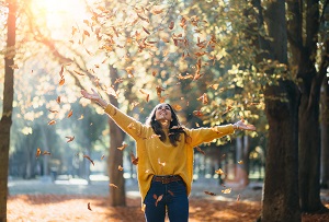 woman having fun throwing leaves in autumn | prepare HOA community for fall