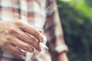 man holding smoking a cigarette in hand | smoking in community associations