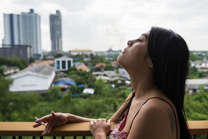 woman smoke cigarette on terrace or balcony of condo | hoa rules on smoking