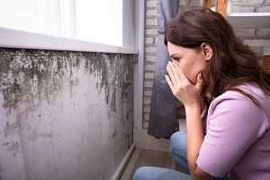 Side View Of A Shocked Woman Looking At Mold On Wall | is mold an hoa problem