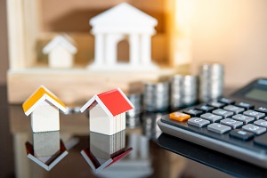 stack of coins, model houses and calculator | HOA increase property values
