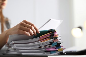 person working on a pile of documents at table | hoa documents