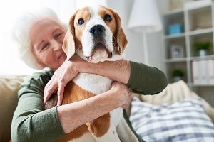 senior woman hugging pet dog | emotional support animals in HOAs