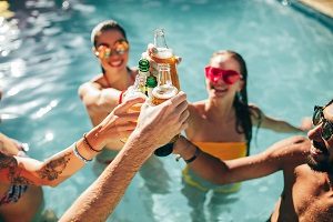 Happy group of people in swimming pool drinking beers | ideas for a HOA summer party
