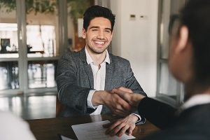 man smiling while shaking hands with another man | hire an HOA management company