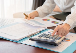 person calculating and reviewing data in financial statement | community association manager