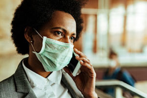 Woman on her phone with a face mask on | covid-19 HOA community guidelines